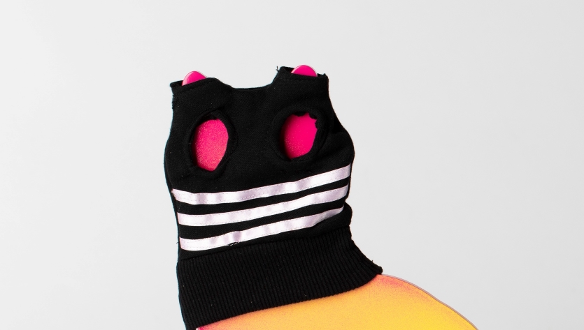 a sculpture of a fluorescent cat wearing a black balaclava against a white background
