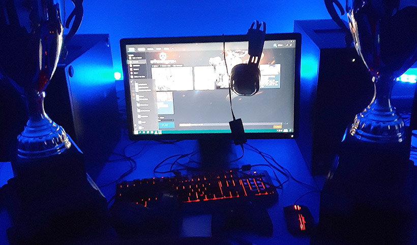 A desktop computer set up in a dark blue lit room 