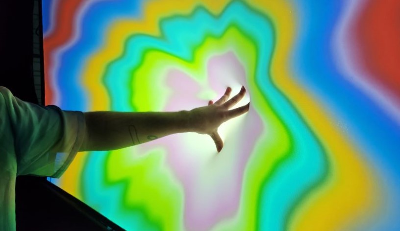 Hand reaching into colourful screen