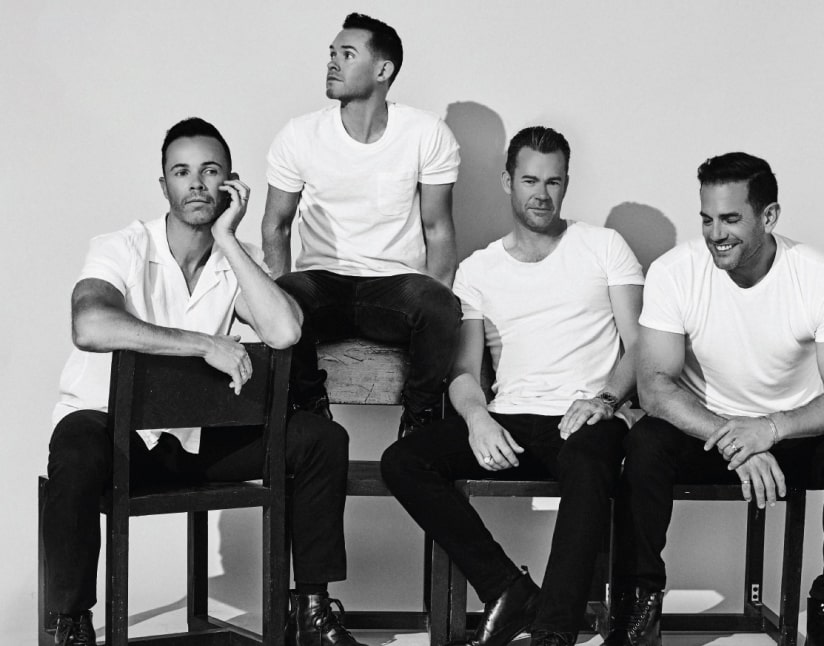 Black and white photo of the for male band members of Human Nature all sitting on chairs