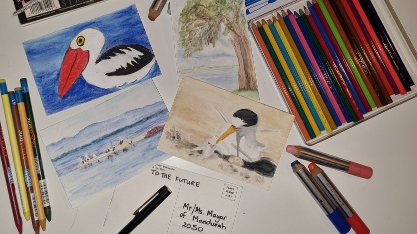 art supplies are scattered across a table with some child-like drawings and paintings of landscape and natural scenes