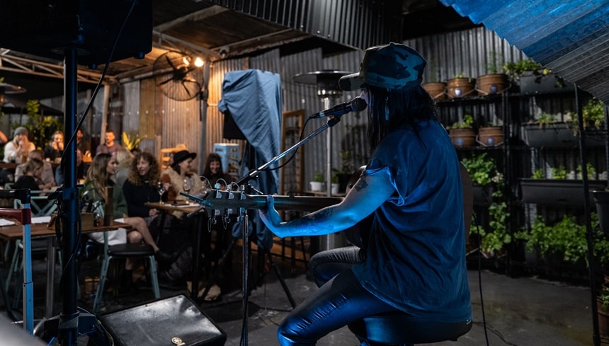 Female acoustic musician performing outdoors at a restaurant.