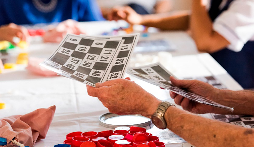 Older persons hands holding bingo cards.