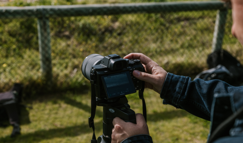 Image of a DSLR camera set-up on a tripod pointing at ocean