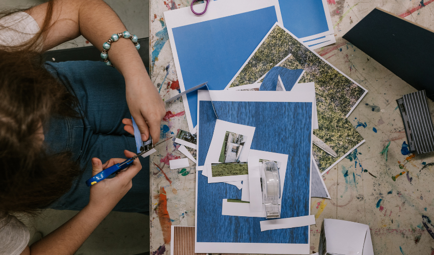 Bird eye view of a child using scissors to cut out an image of a tiny house