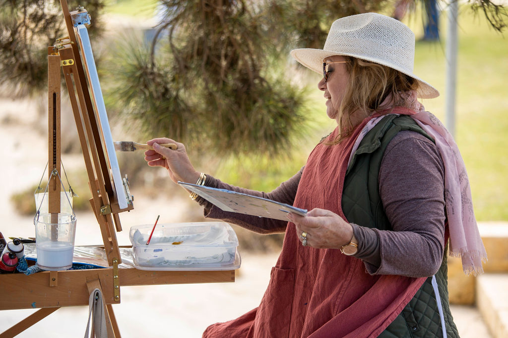 Female painting outdoor wearing a hat 