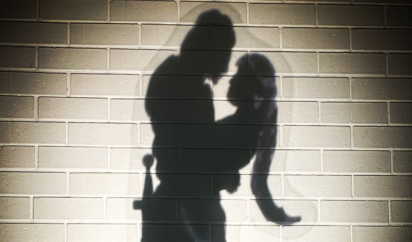 The outline of a man holding a woman projected onto a white wall