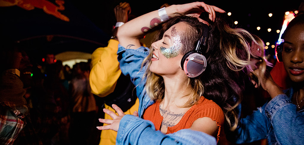 Lady with electric inspired face painting dancing with headphones on 