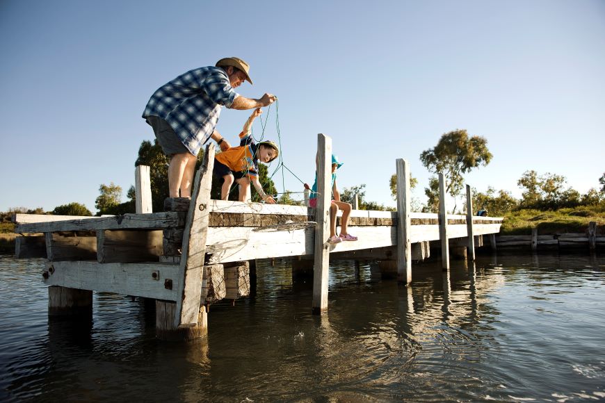 Male crabbing off a jetty with two young children