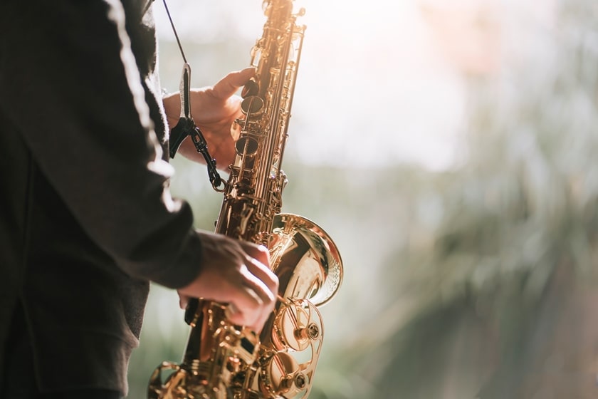 Close-up of mans hands and body playing a gold saxophone