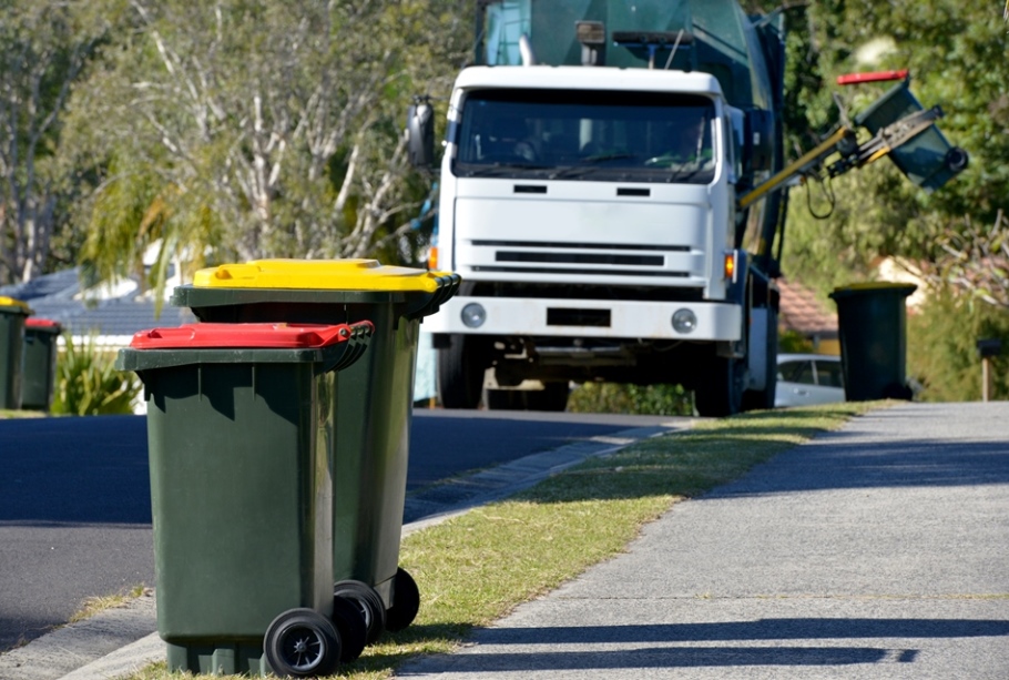 Rubbish truck coming down the street towards rubbish bins