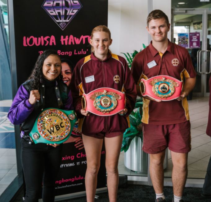 Two students stand side by side with world boxing champion Louisa (Bang Bang Lulu) Hawton