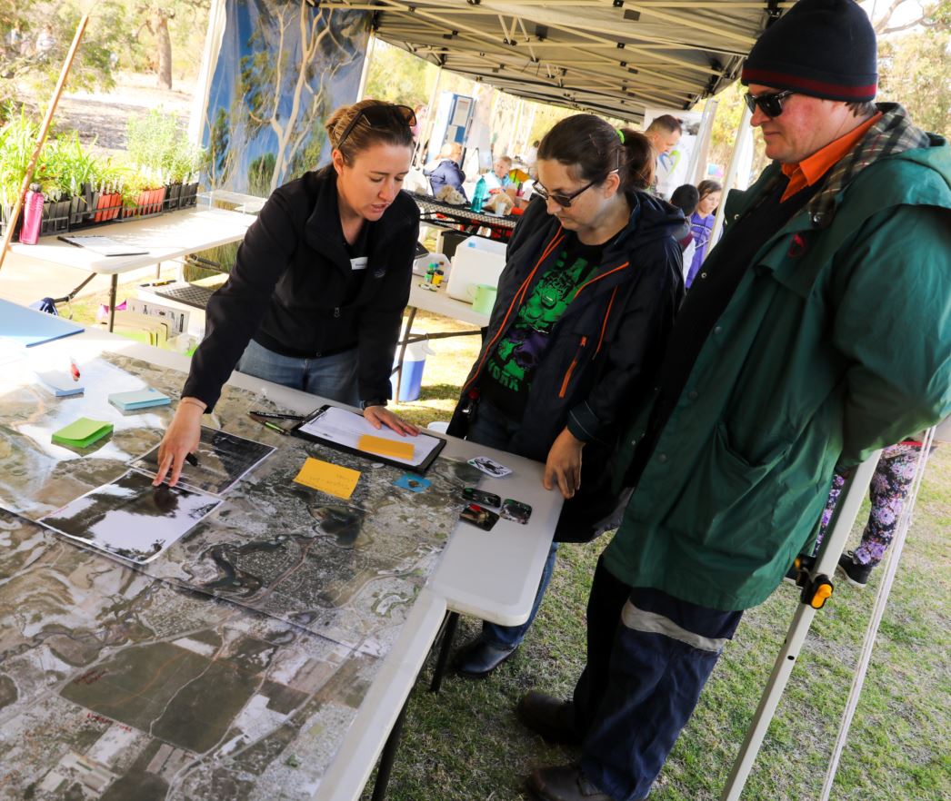 Environment education officer speaking to people and pointing to maps