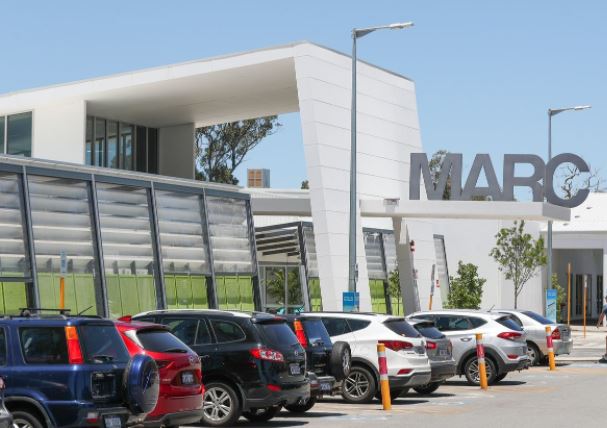 Front view of Mandurah Aquatic and Recreation Centre building with cars in foreground