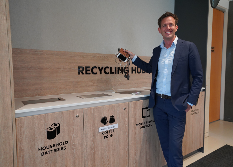 Mayor Rhys Williams dropping off e-waste at the City's recycling hub City of Mandurah Mayor Rhys Williams holding a phone and some charging cords above a cabinet with a number of bins installed labelled "household batteries", coffee pods, "mobile phones and devices". There is a sign above the cabinets that says "recycling hub"
