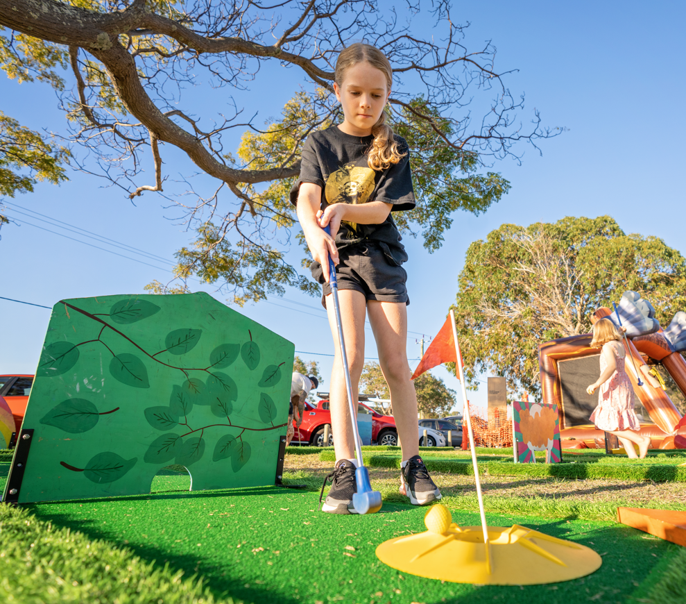 Young girl plays mini golf outdoors