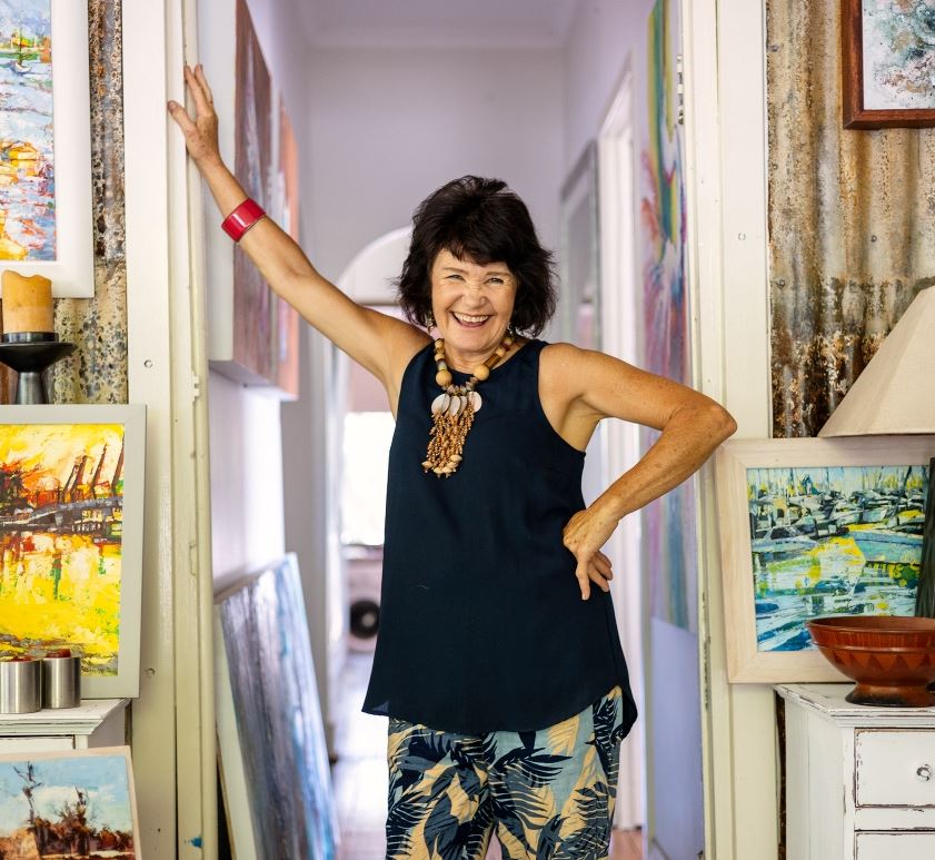 woman stands leaning on a wall surrounded by art
