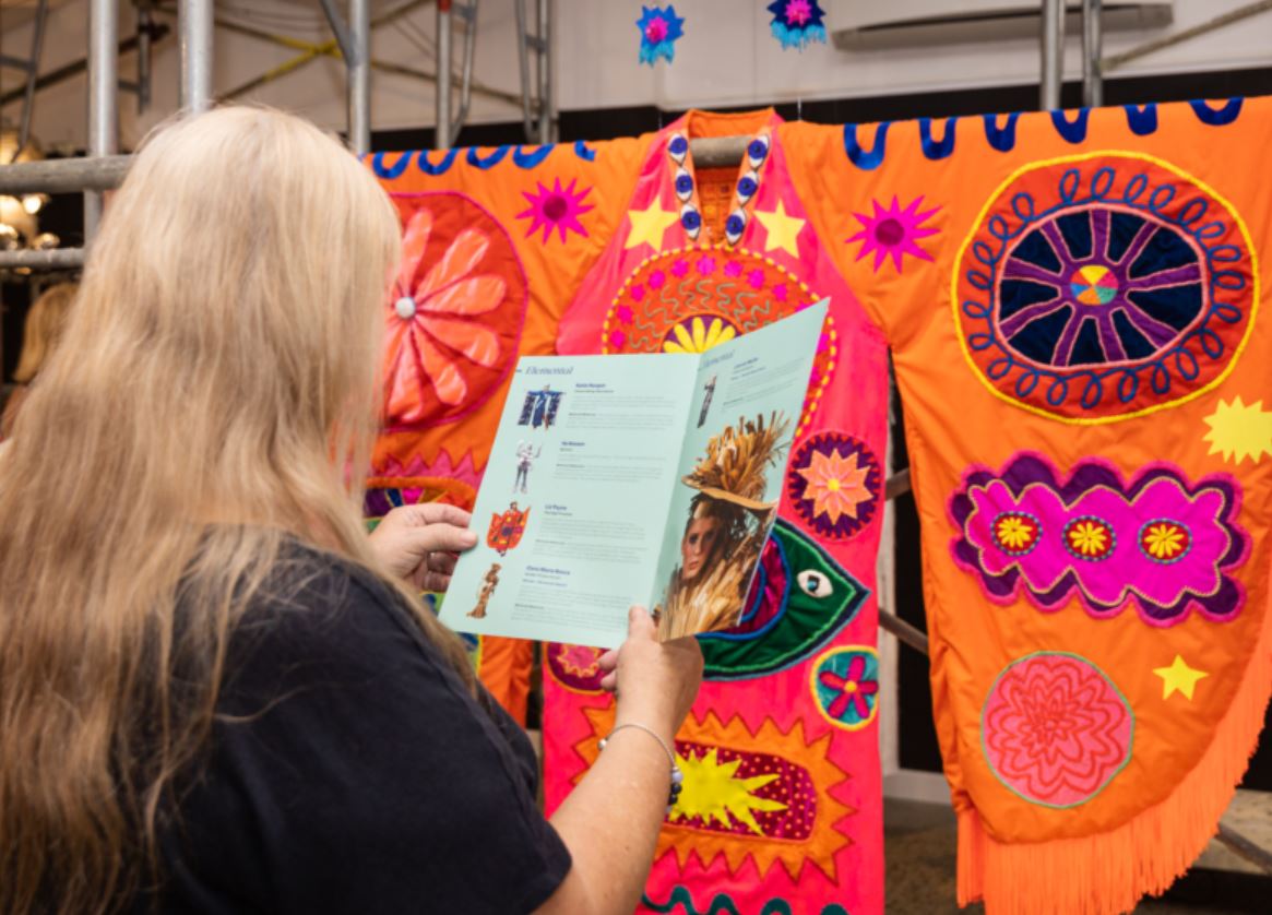Woman reads program while looking at colourful artwork