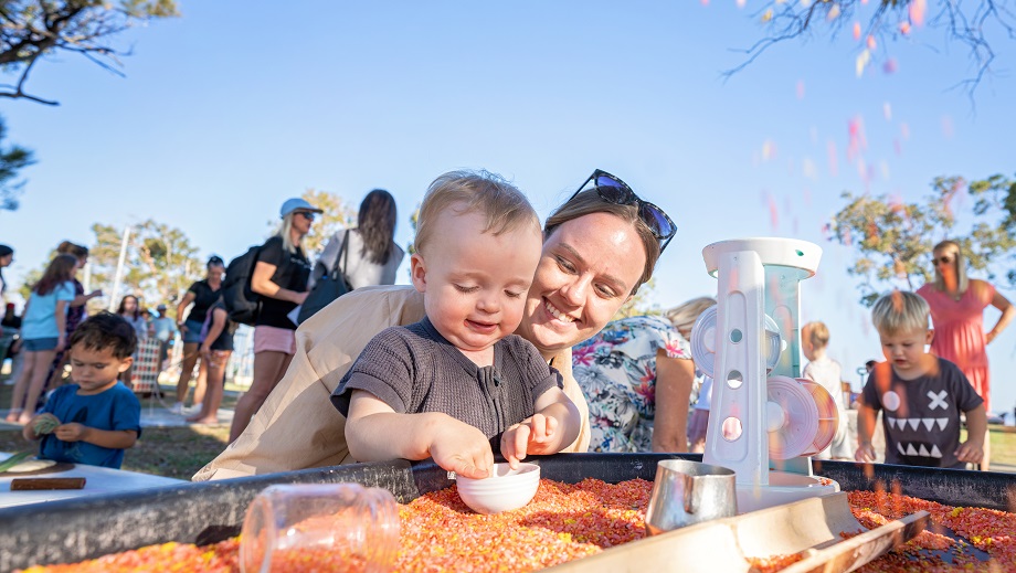 A mother with her child playing at a sensory station at a community event