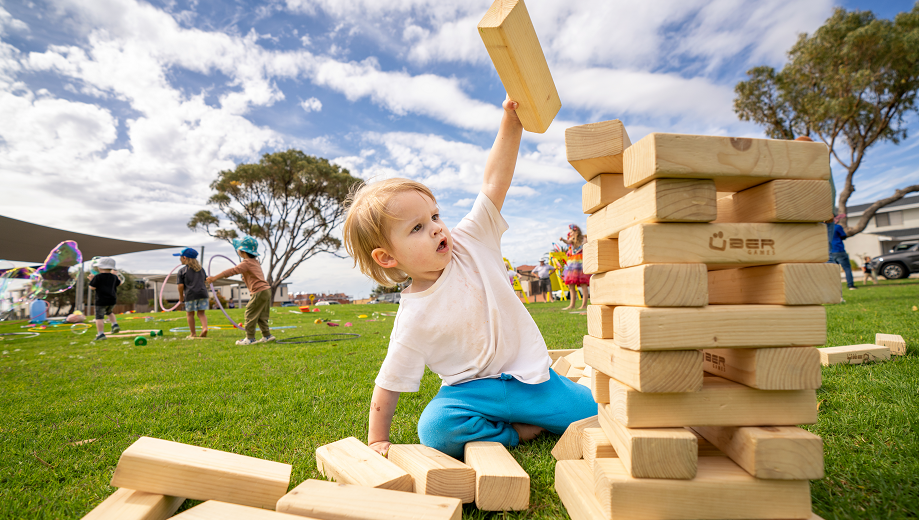 Young child playing with giant Jenga on the foreshore reserve