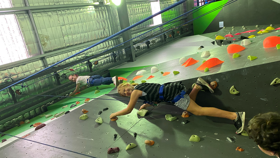 Two teens doing indoor rock climbing.