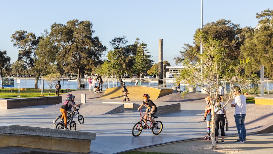 Children on bikes at a skatepark while family watches on