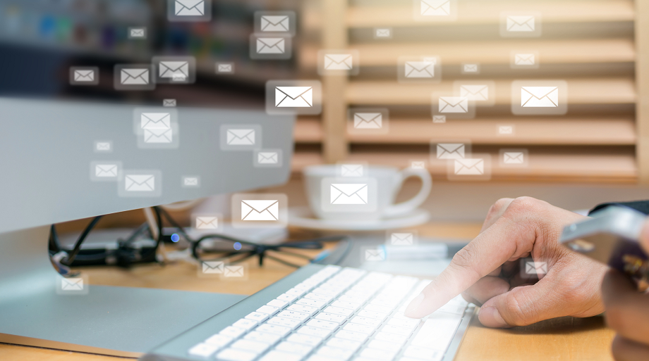 Hand typing on a computer keyboard with the other person's hand holding a mobile phone