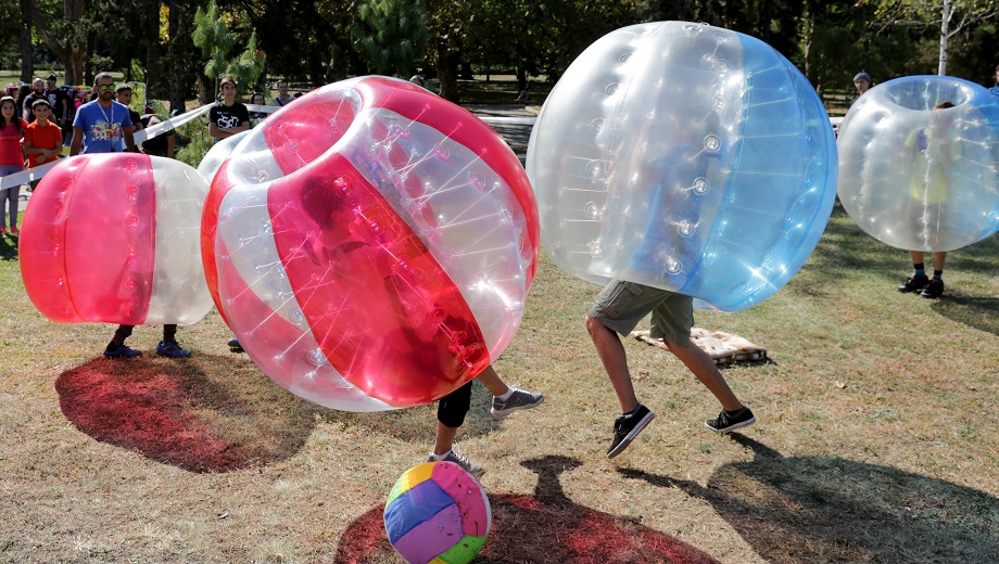 Kids playing bubble soccer and trying to kick a ball.