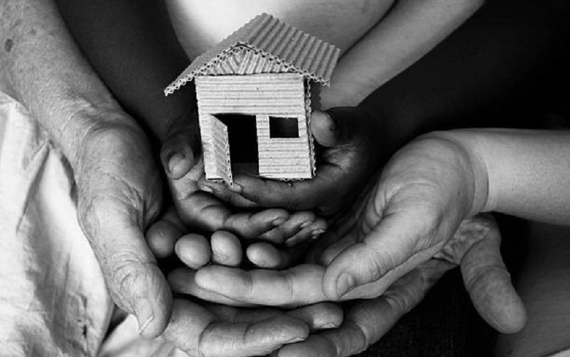 Black and white photo of hands around a little house