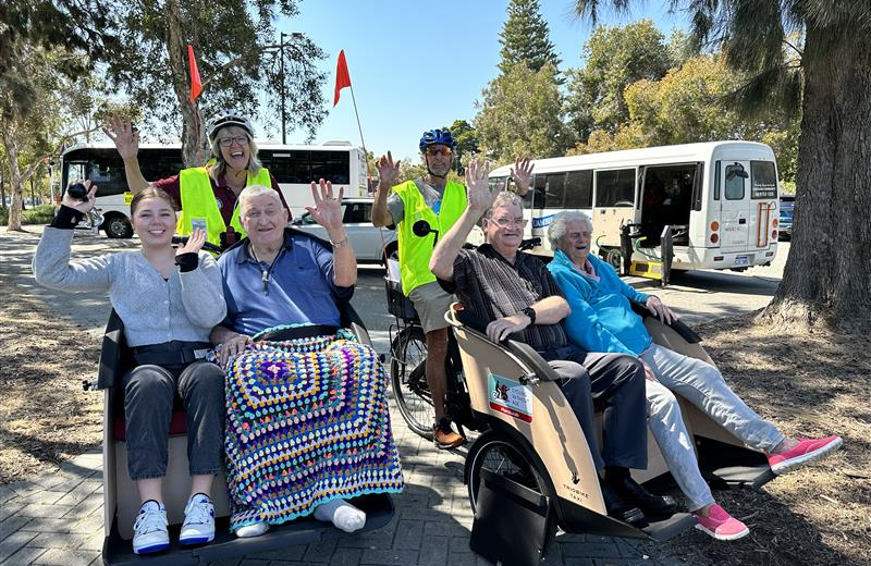 Four people sitting in trishaws being rode by Cycling Without Age volunteers