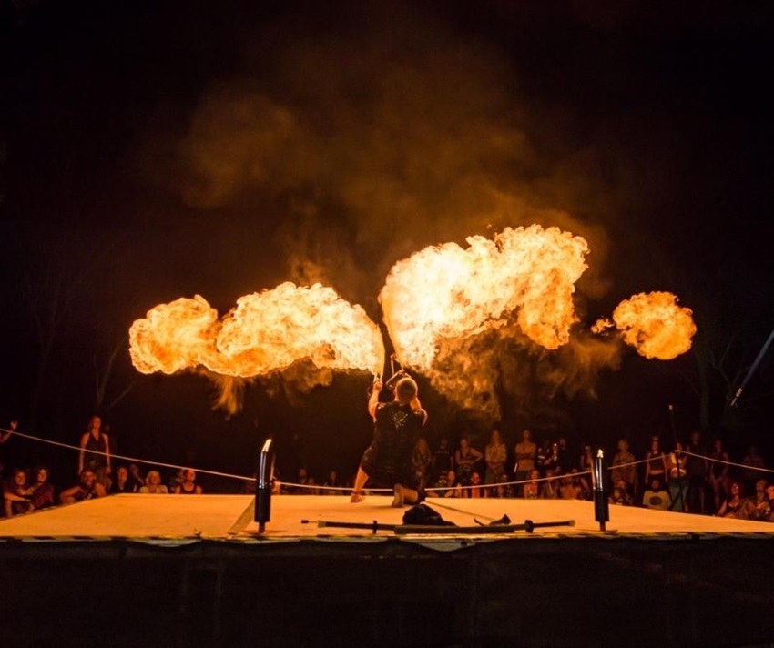 Fire performer on stage with crowd behind him