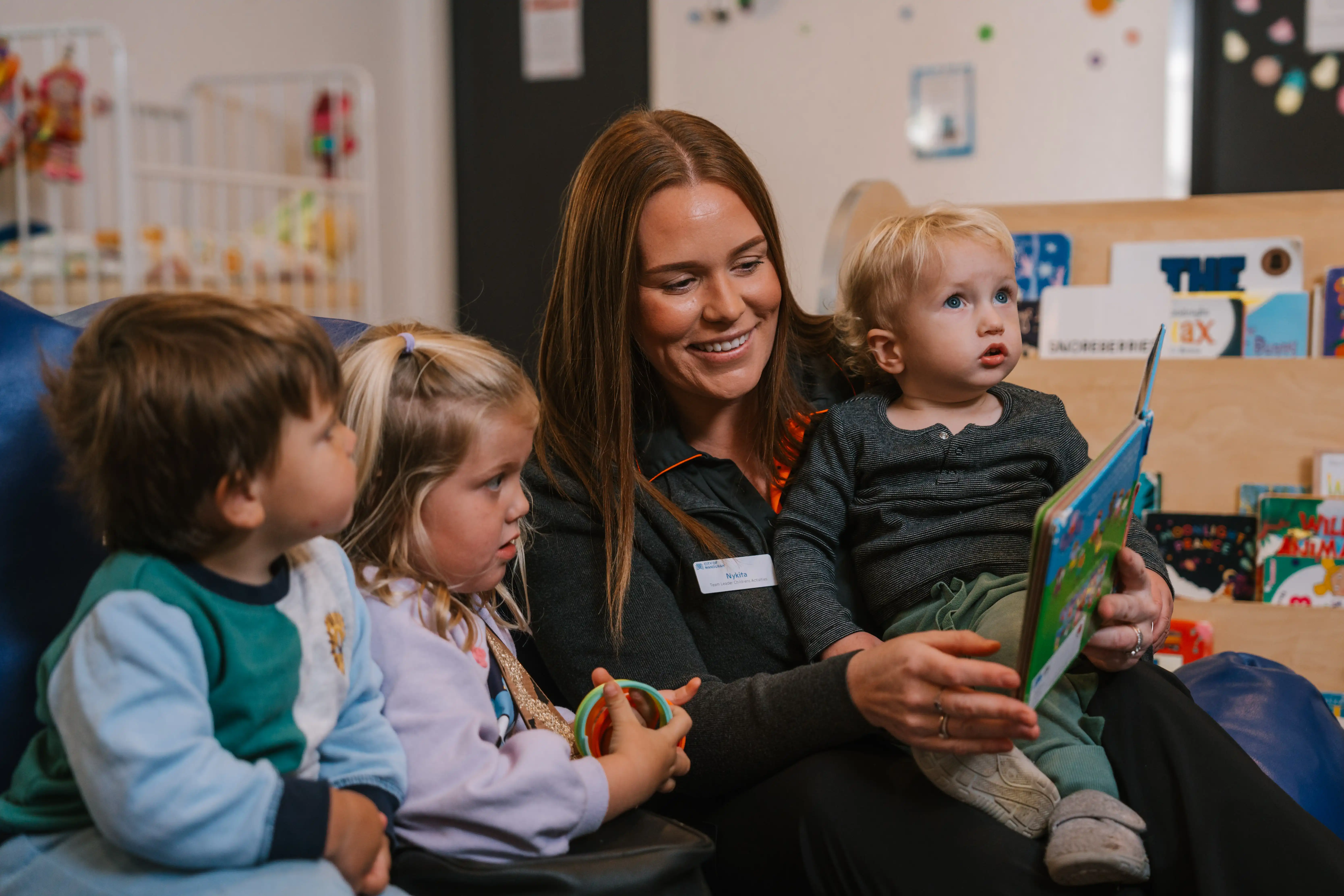 Creche staff member reading books to children.