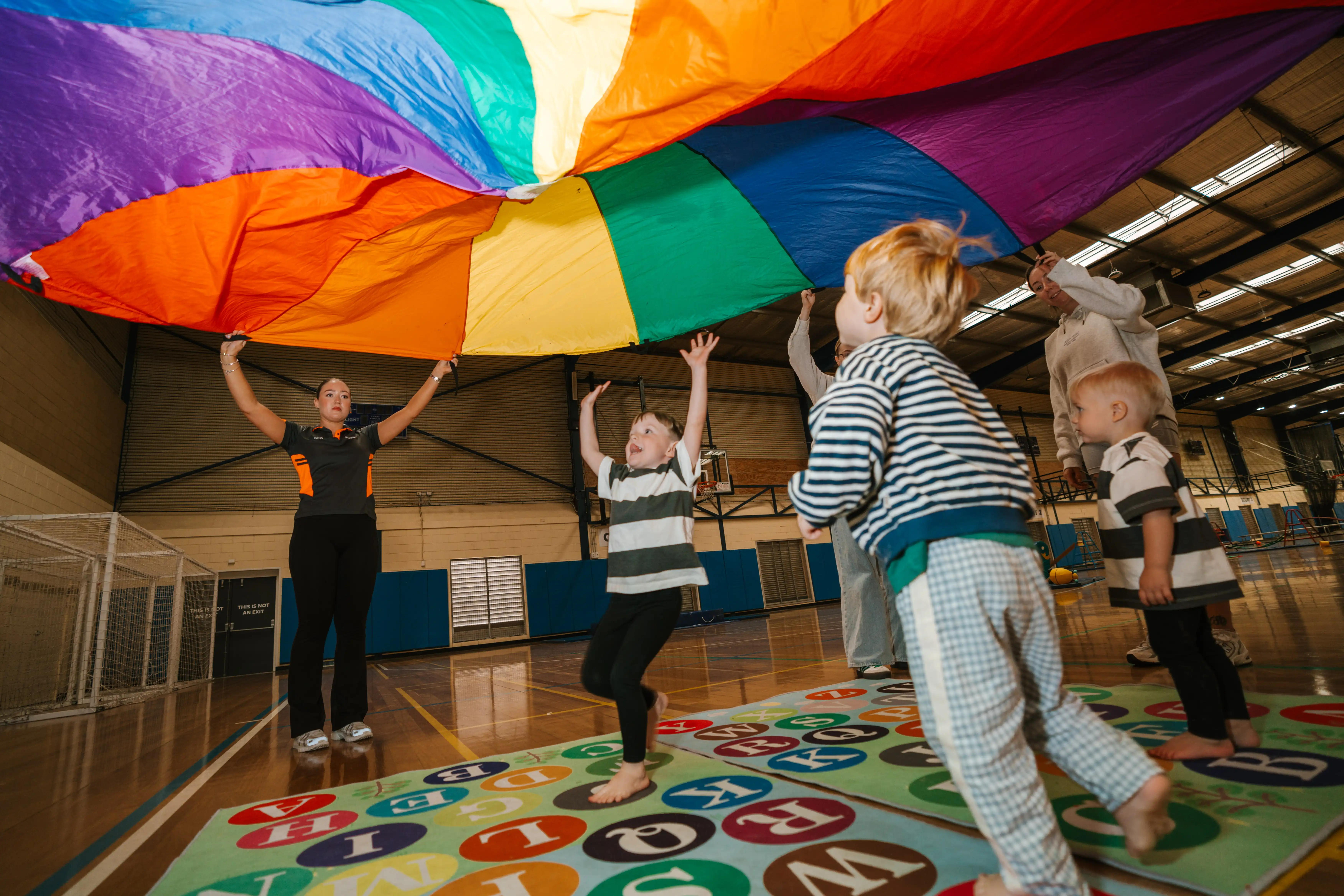 Children running under colourful parachute.