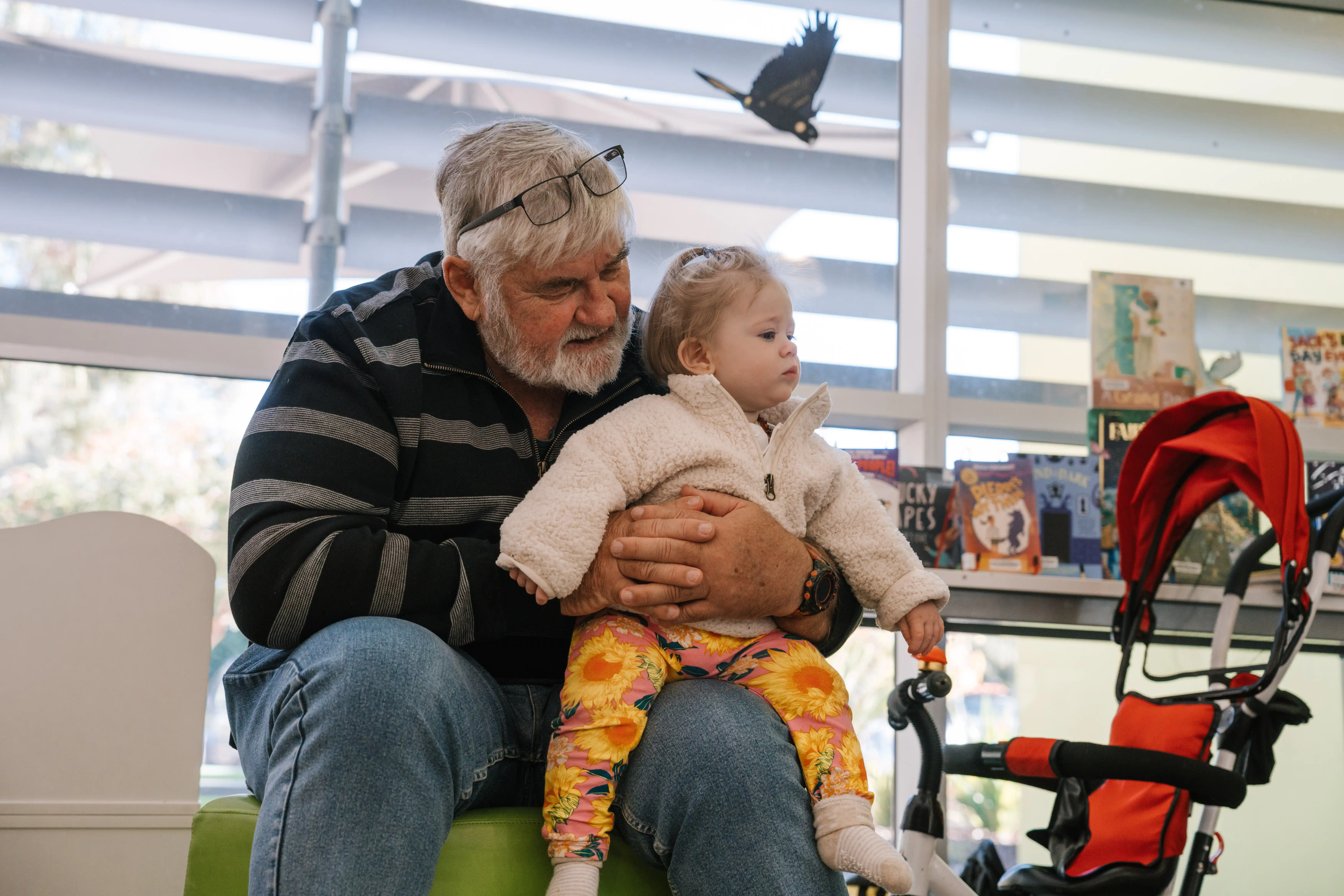 Adult holding child on knee while at library.