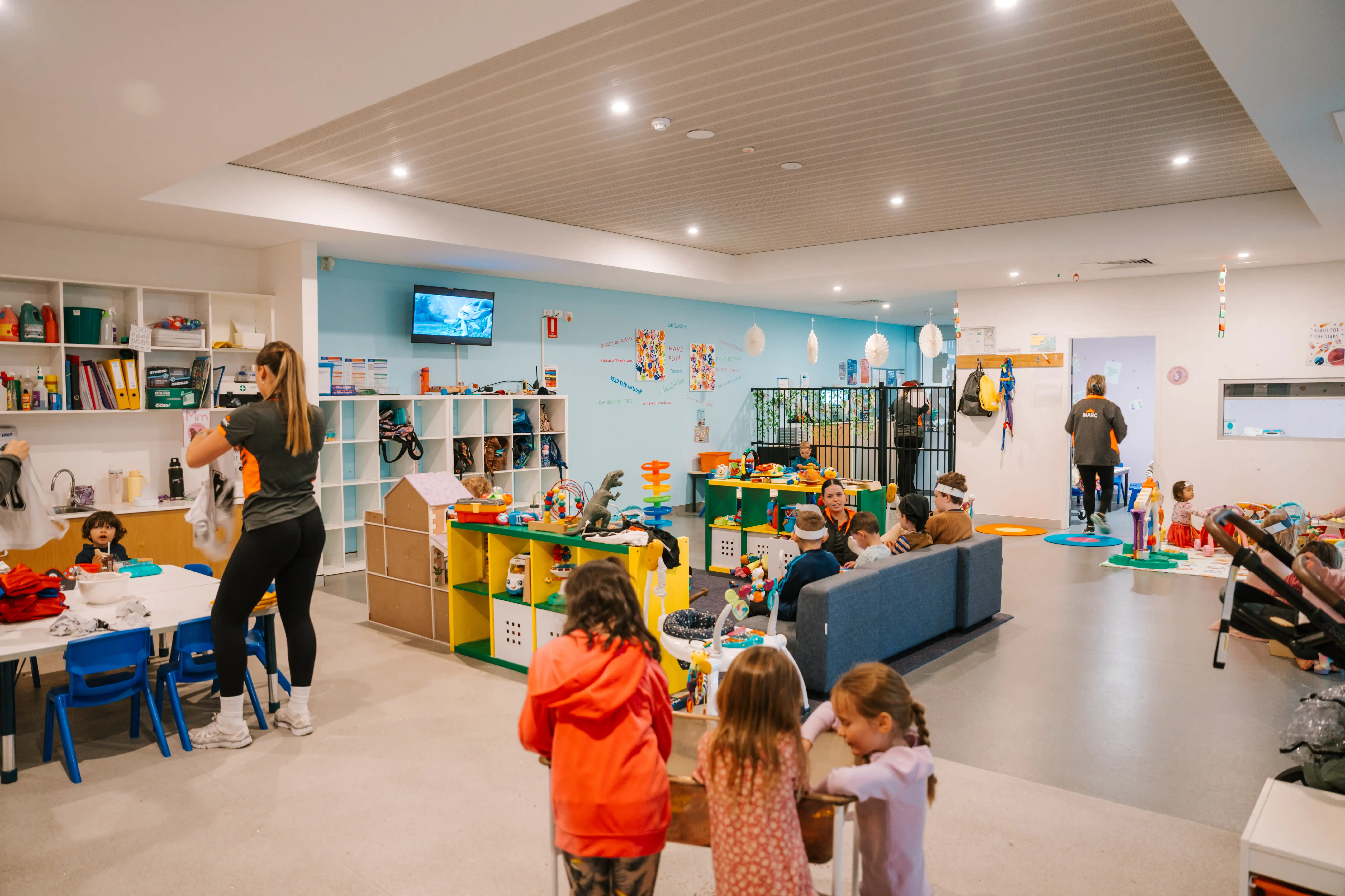 Children and carers playing in a bright indoor crèche at the MARC