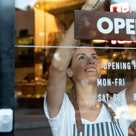 Person putting up sign in window of business.